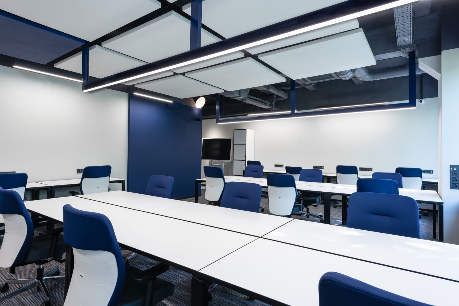 Air balancing — modern Class A commercial office with exposed ductwork above blue training-room seating