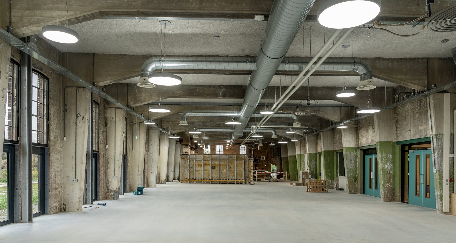 Air balancing — large commercial industrial space with overhead galvanized supply ductwork ready for TAB verification under ASHRAE 111