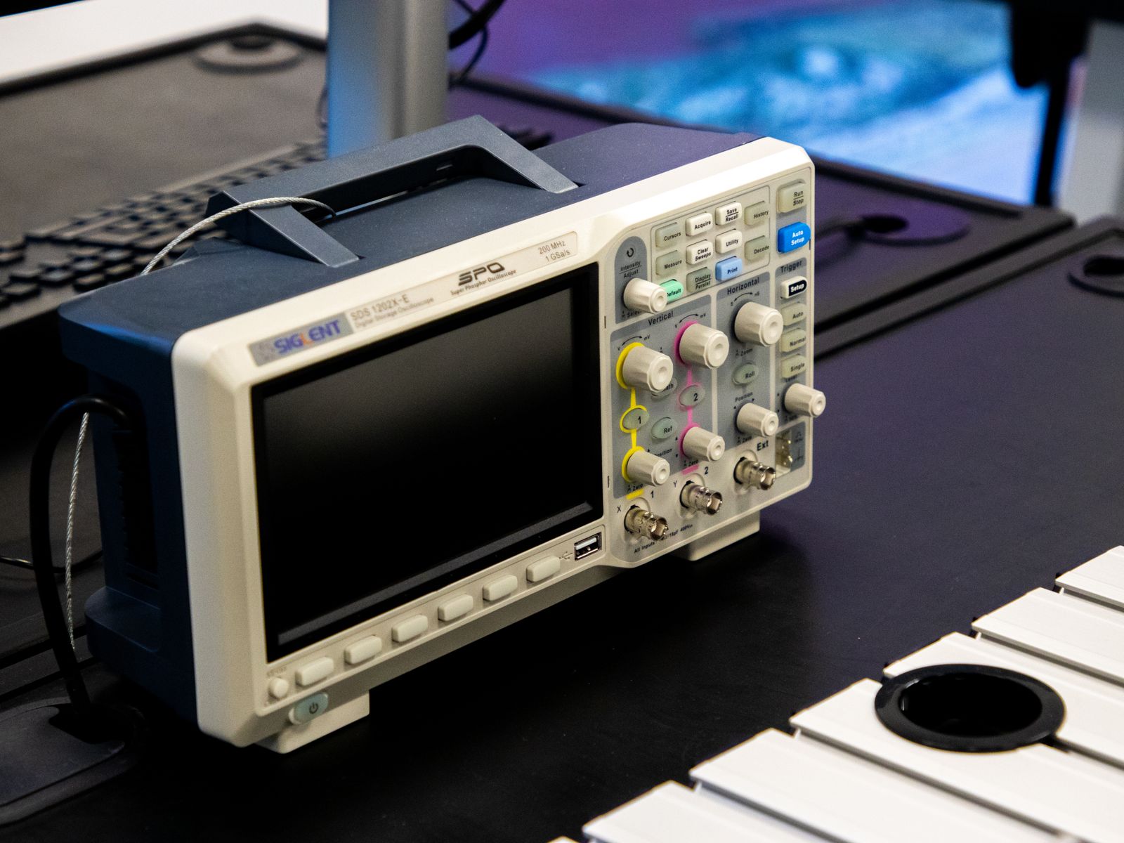 Sound and vibration testing — digital oscilloscope on a lab workbench used for HVAC vibration frequency analysis