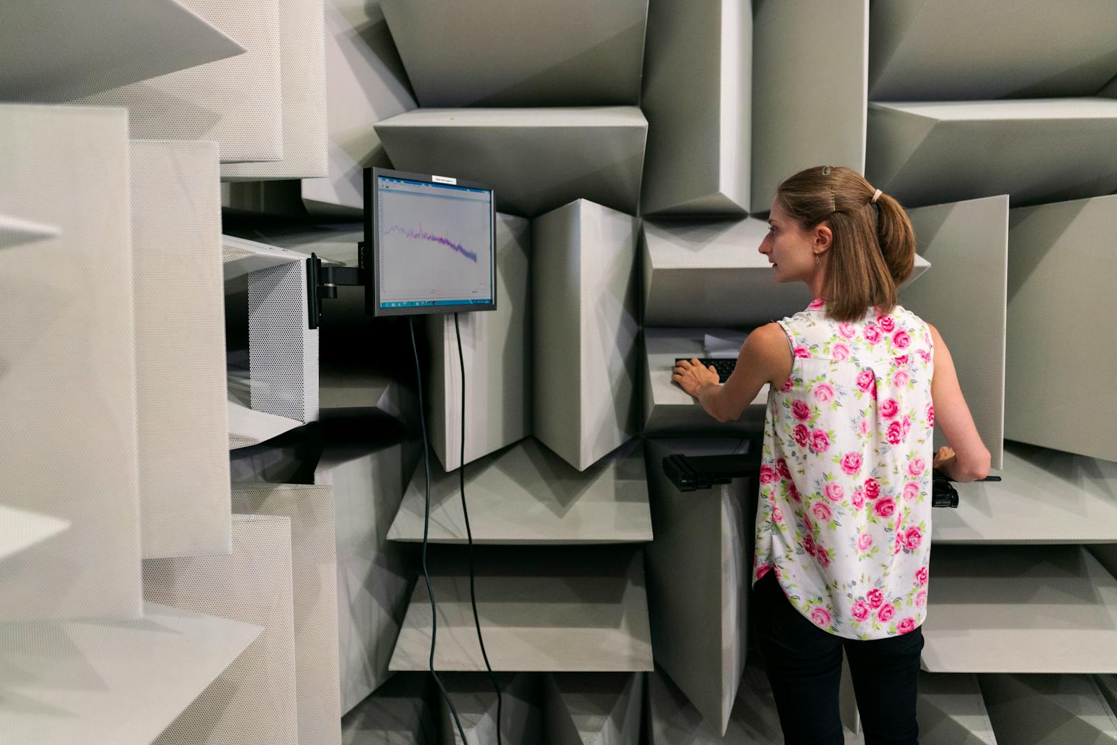 Sound and vibration testing — engineer measuring sound waves in an anechoic chamber with FFT analyzer on monitor