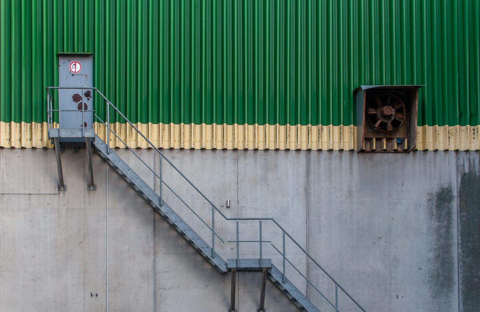 Stairwell pressurization testing — industrial exterior with metal stairway access and exhaust ventilation fan on a commercial building